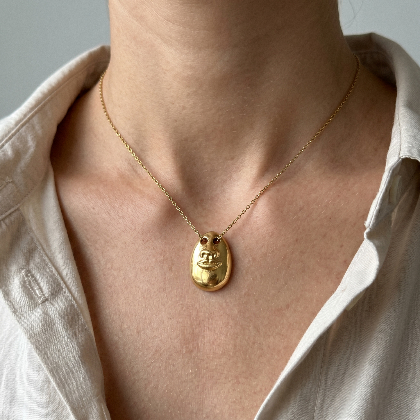 Model wearing the Hear No Evil gold pendant necklace on a fine chain