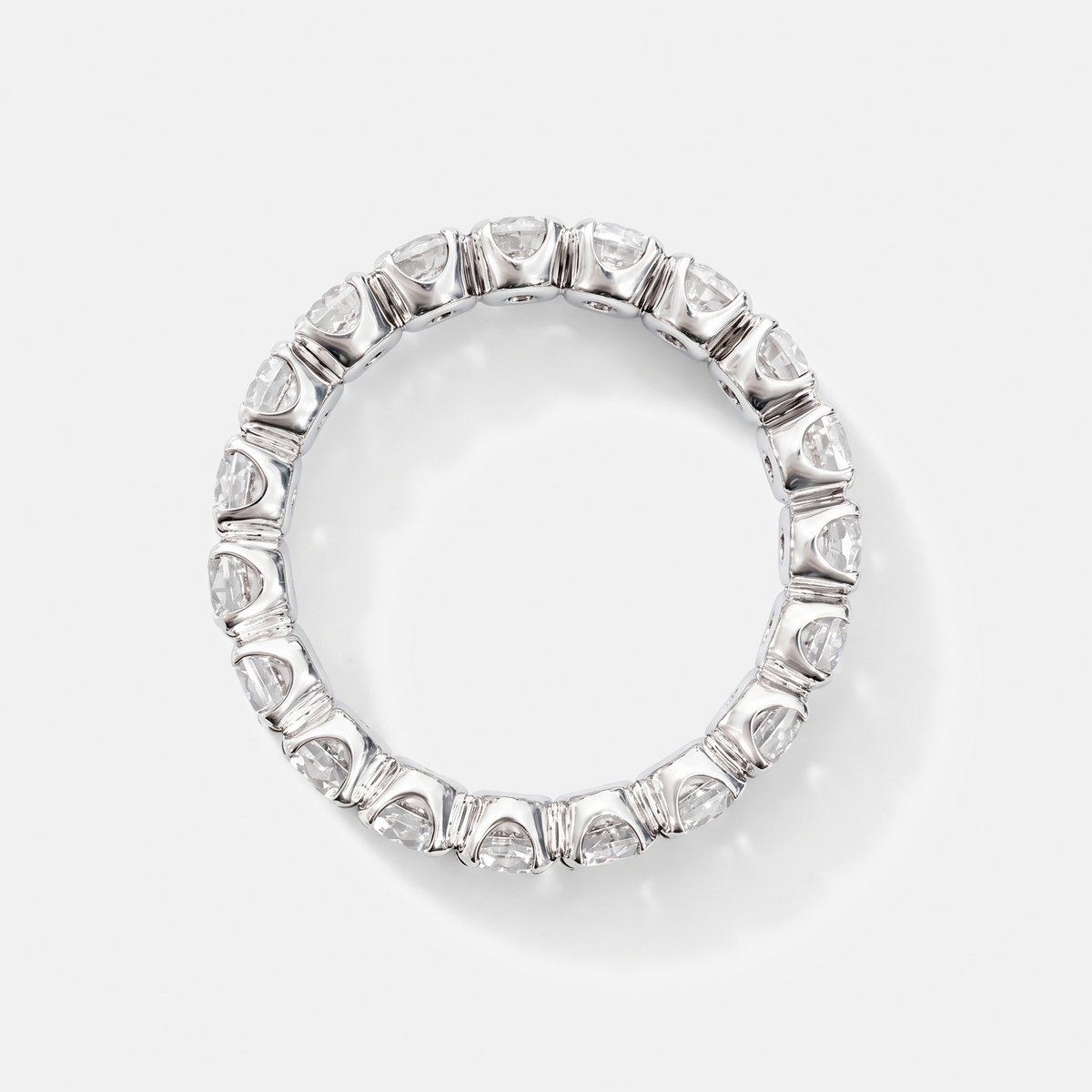 A silver-toned eternity ring featuring a continuous row of heart-shaped clear gemstones in a prong setting, photographed on a clean light gray background.