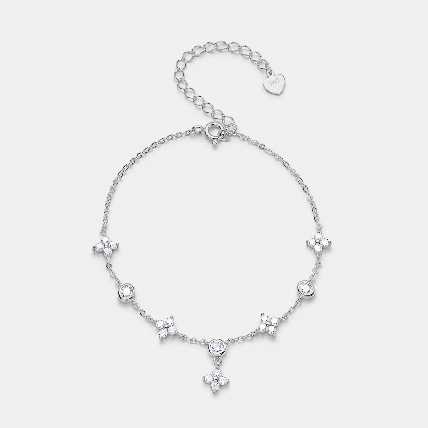 A delicate silver chain bracelet featuring five small floral star motifs and a central round clear stone, with an adjustable lobster clasp and heart-shaped tag, shown on a light gray background.