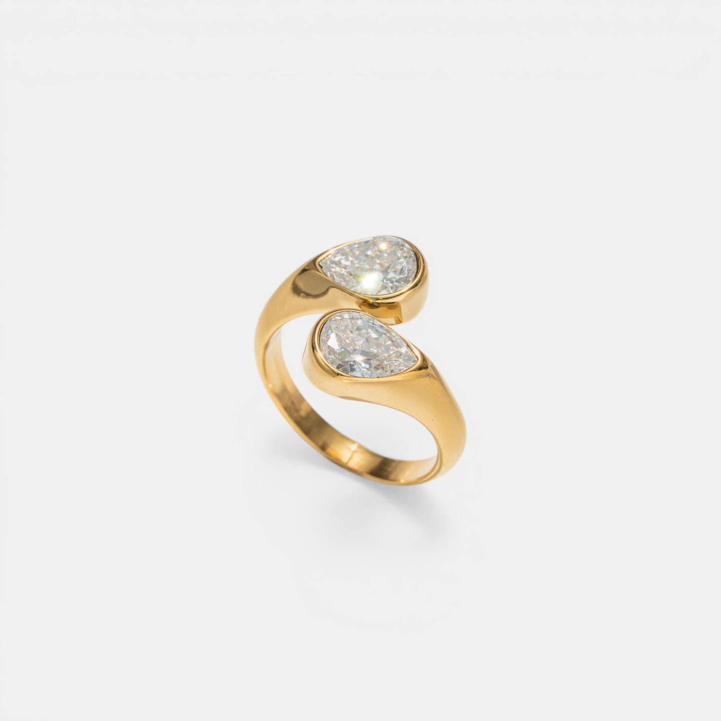 A gold wrap ring featuring two teardrop-shaped clear gemstones, photographed on a clean, light gray background.