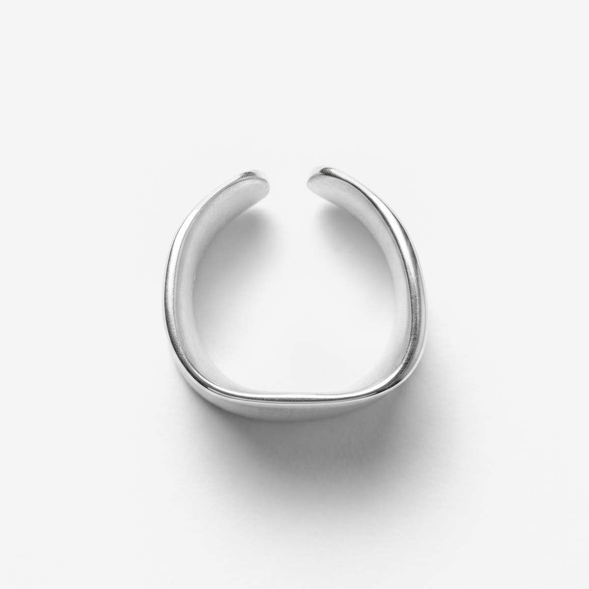 A minimalist silver-toned metal ring with a wide, open, U-shaped design, photographed on a clean white background with a soft shadow.