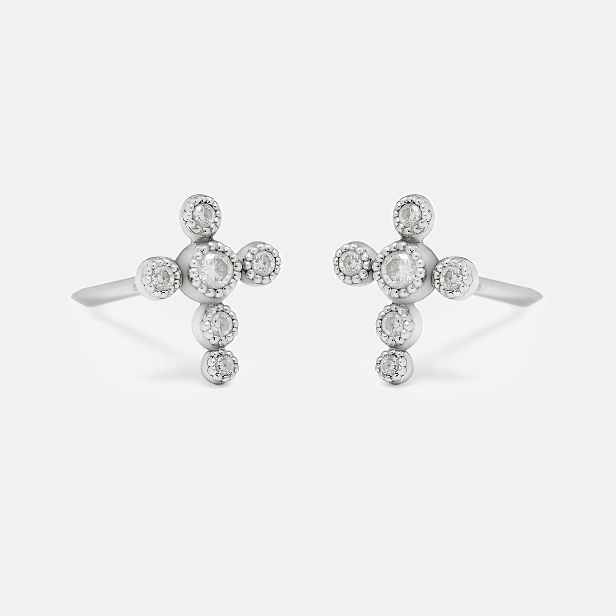A pair of silver-toned cross-shaped earrings with small clear round stones, photographed on a clean light gray background.