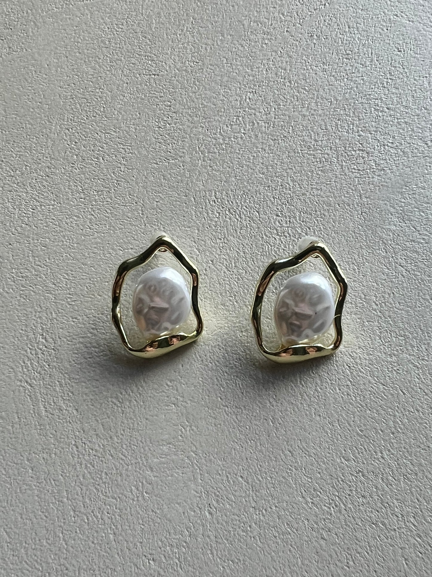 Pair of earrings with a textured design on a beige surface