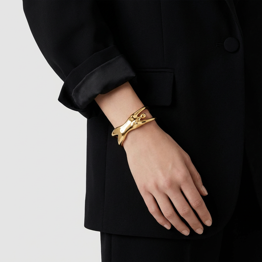 Gold bracelet on a person's wrist with a black coat background