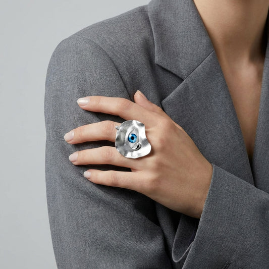 Person wearing a silver ring with a blue gemstone on a gray background
