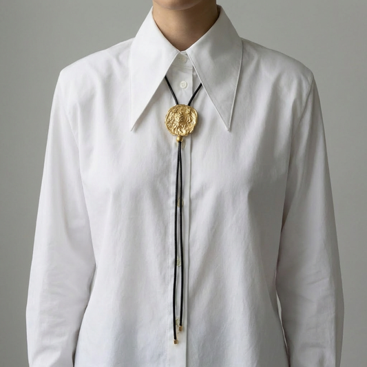 Gold bolo tie with black cord on a gray background