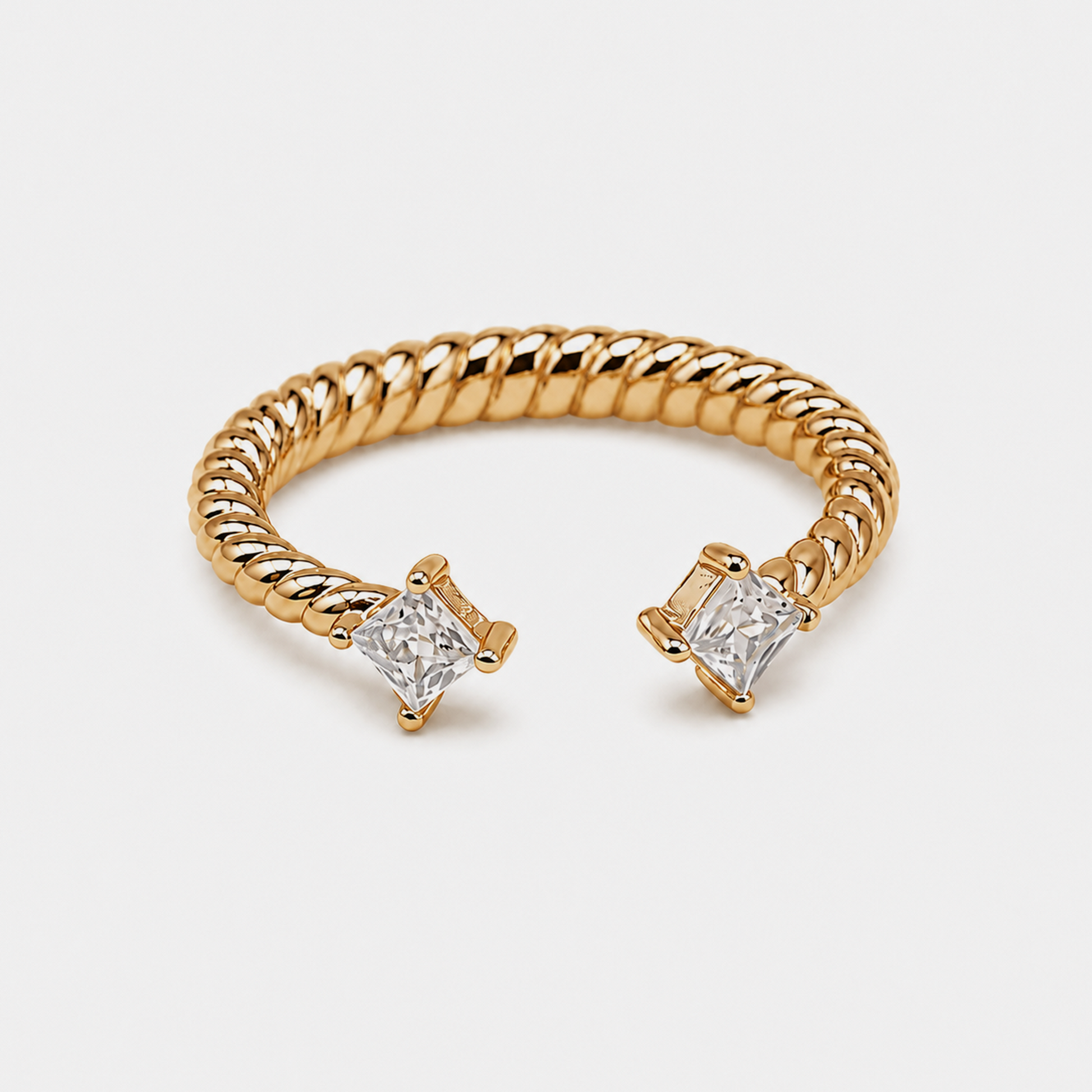 A gold rope-style cuff ring with two princess-cut clear gemstones in prong settings, shown on a light gray background.