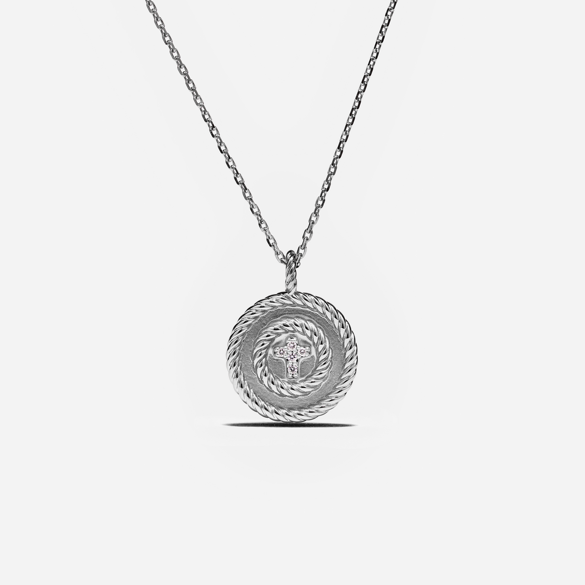 A silver necklace with a circular pendant featuring a textured rope-like outer border and a central star motif, shown against a light gray background.