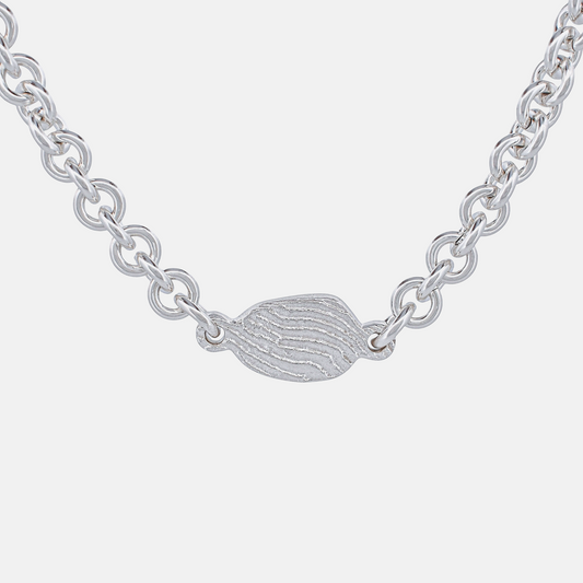 Silver chain necklace with a small, detailed pendant on a white background