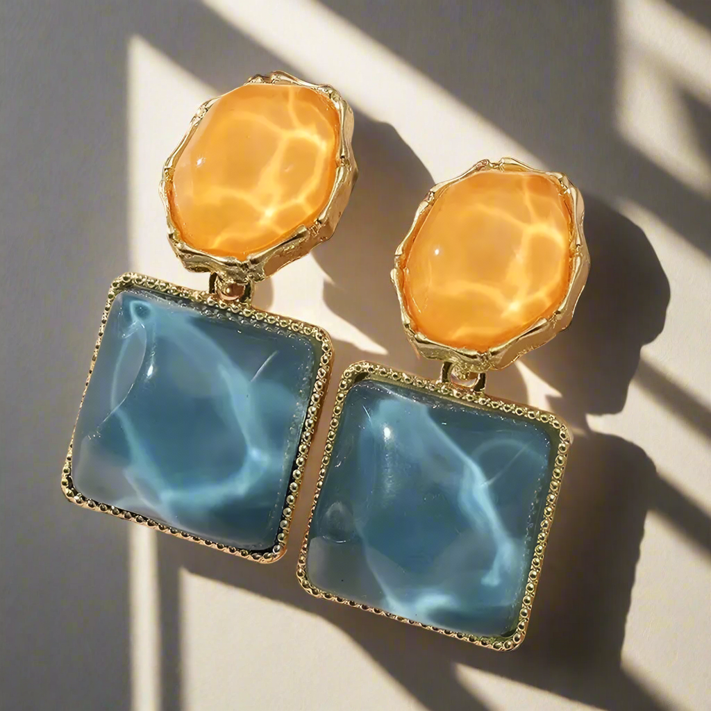 Pair of earrings featuring orange and blue stones on a light background