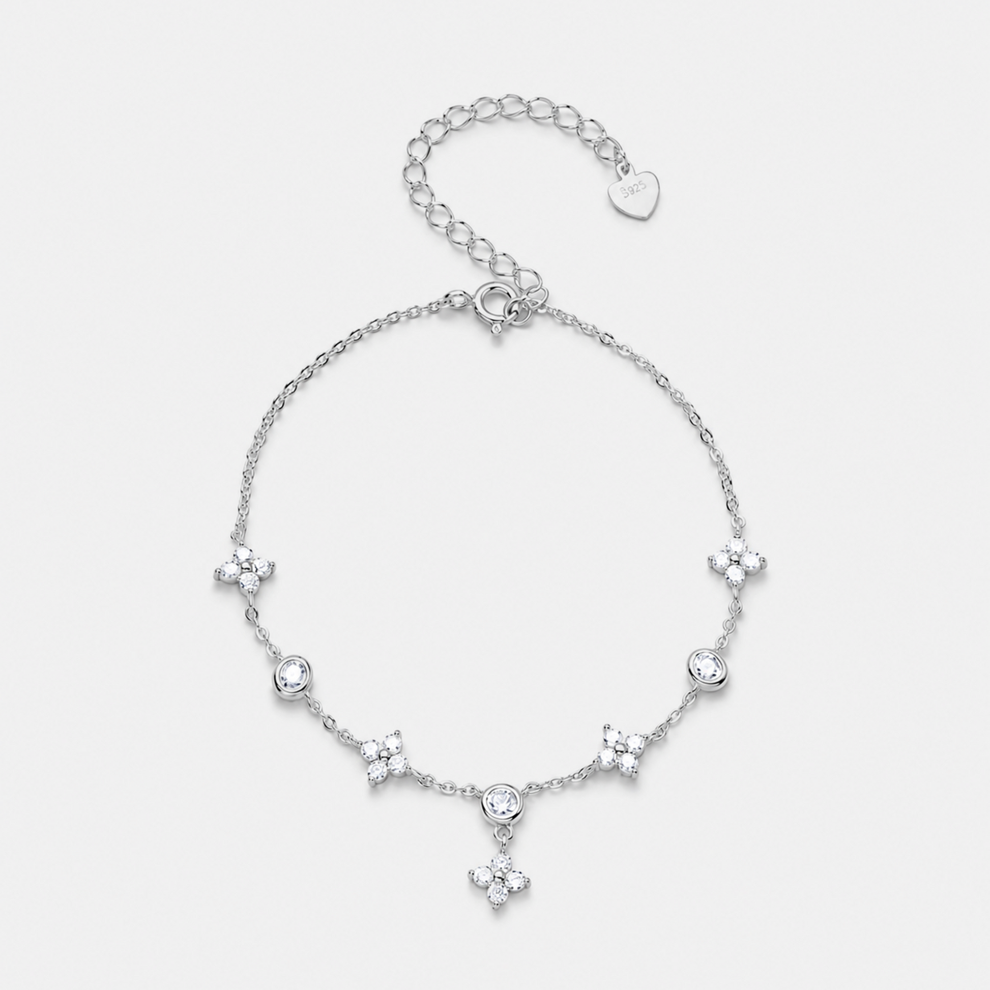 A delicate silver chain bracelet featuring five small floral star motifs and a central round clear stone, with an adjustable lobster clasp and heart-shaped tag, shown on a light gray background.