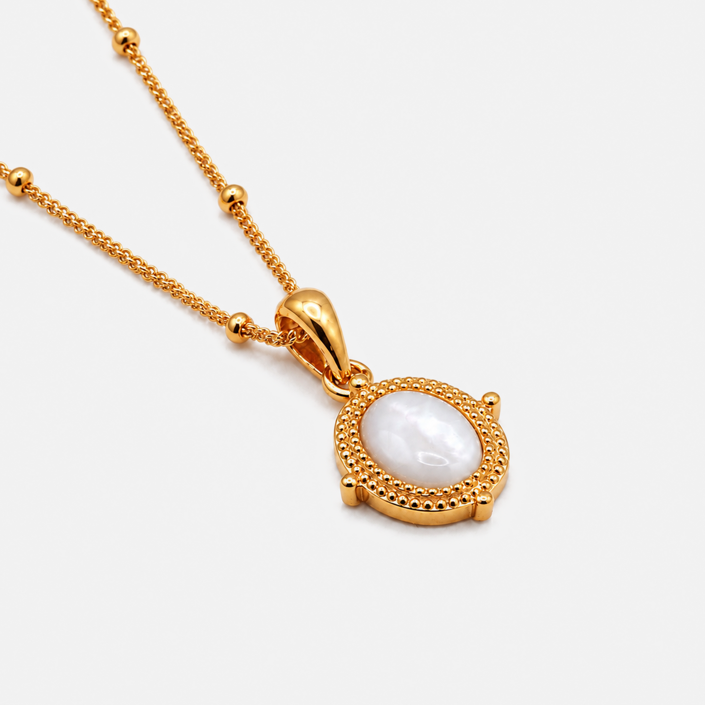 A gold chain necklace with a round pendant featuring a textured gold bezel and a smooth, white mother-of-pearl center stone, shown on a light gray background.