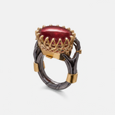 Luxury statement ring with large red gemstone held by sculptural black hands in gold setting, designer jewellery piece