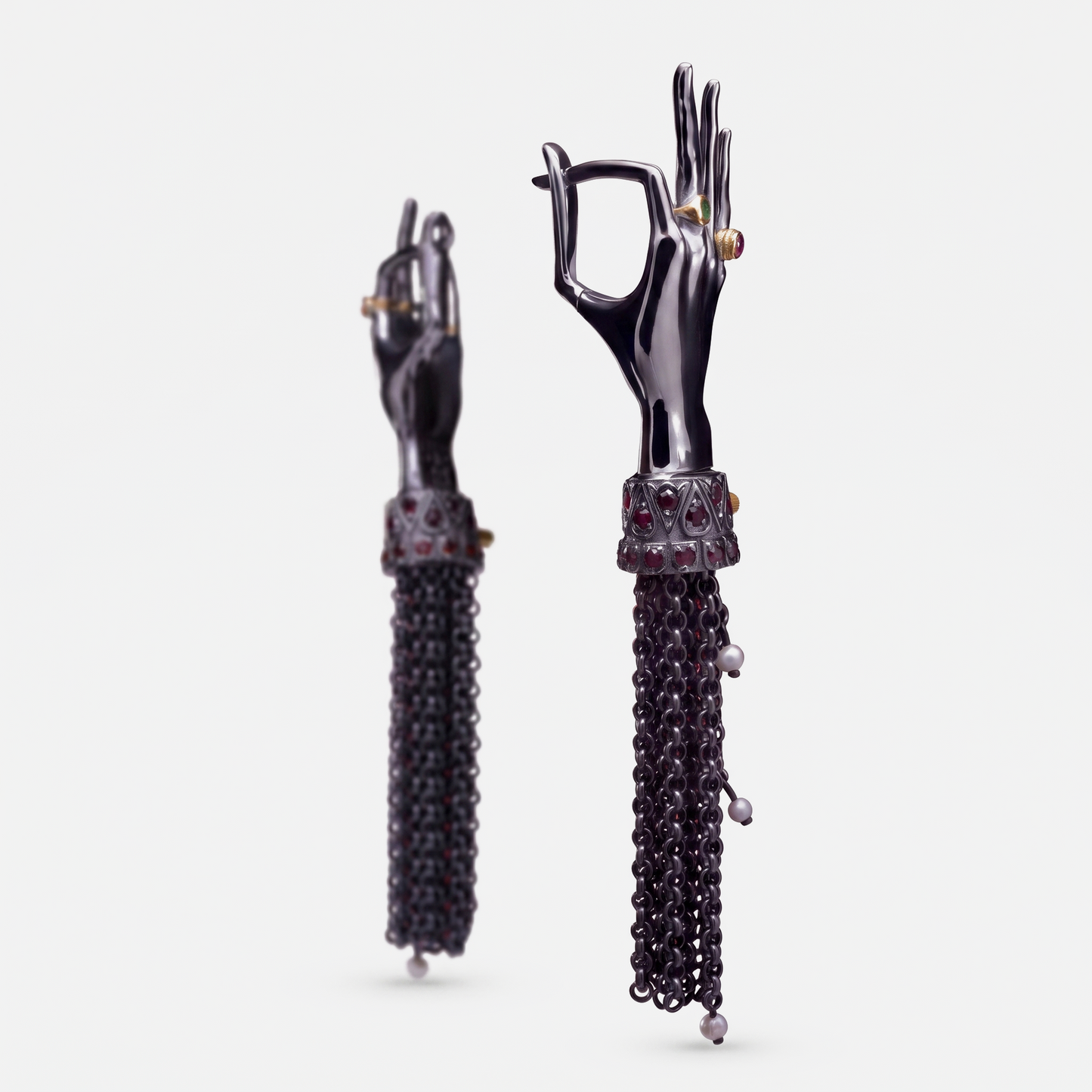 Black hand-shaped earrings with articulated fingers, gemstone details and long chain tassels, contemporary jewellery design