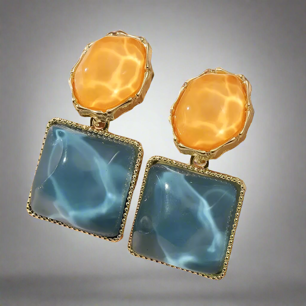 Pair of earrings featuring orange and blue stones on a light background