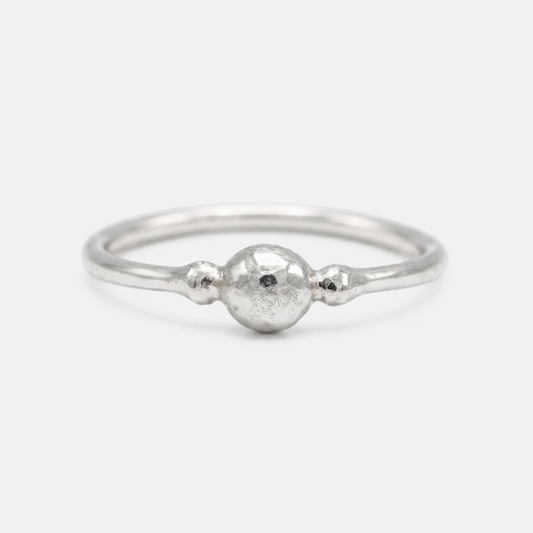 A silver ring with a textured, hammered finish and a small spherical bead detail on the band, photographed on a clean white background.
