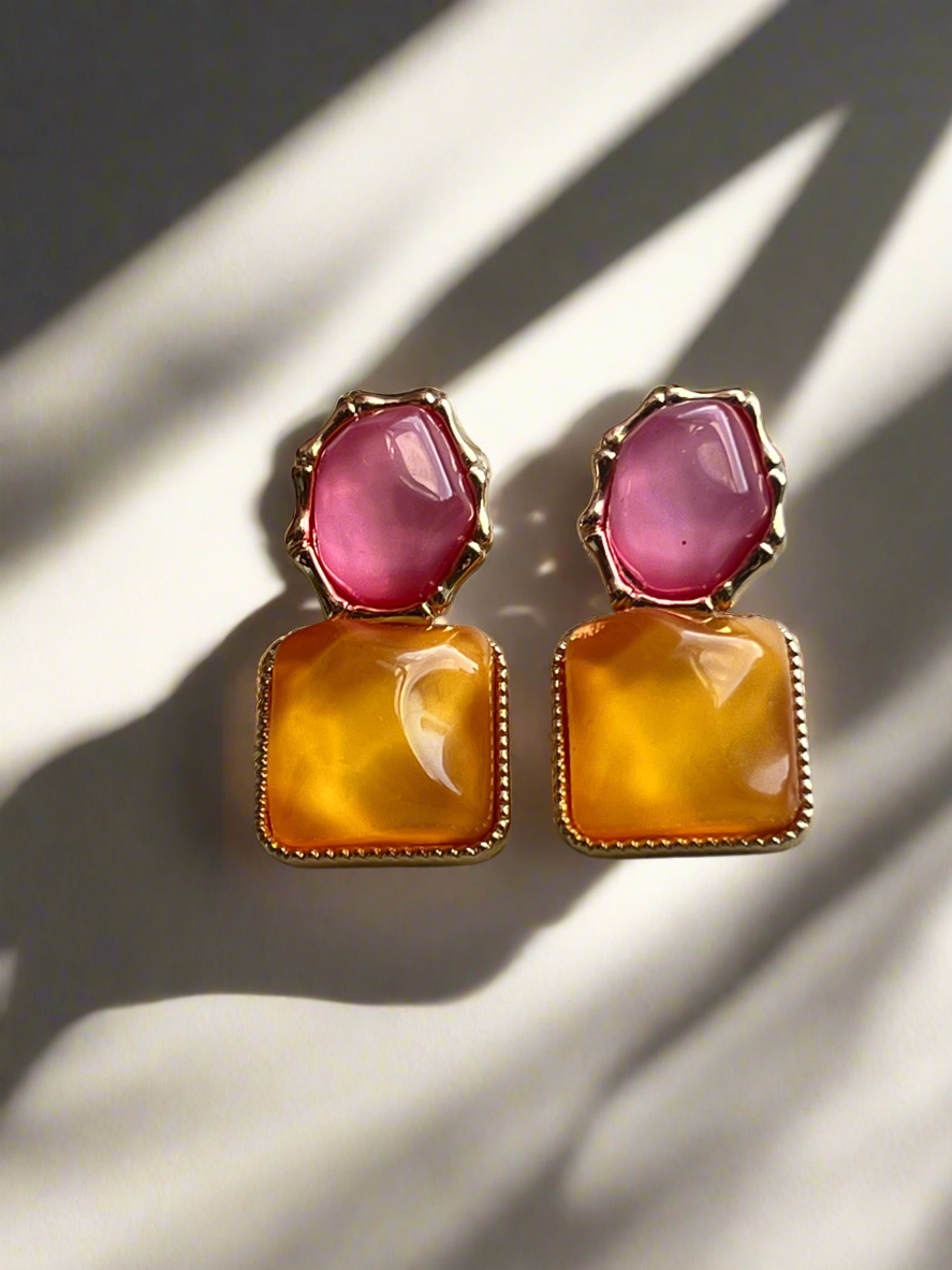 Pair of earrings with pink and orange stones on a light background