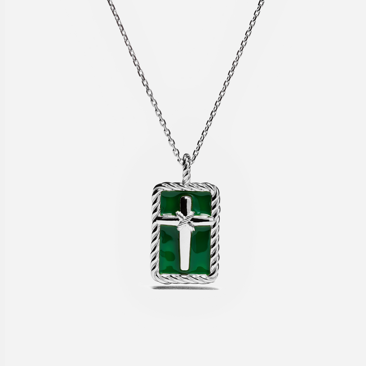 A silver chain necklace with a rectangular pendant featuring a green inlay and a silver cross in the center, set against a light gray background.