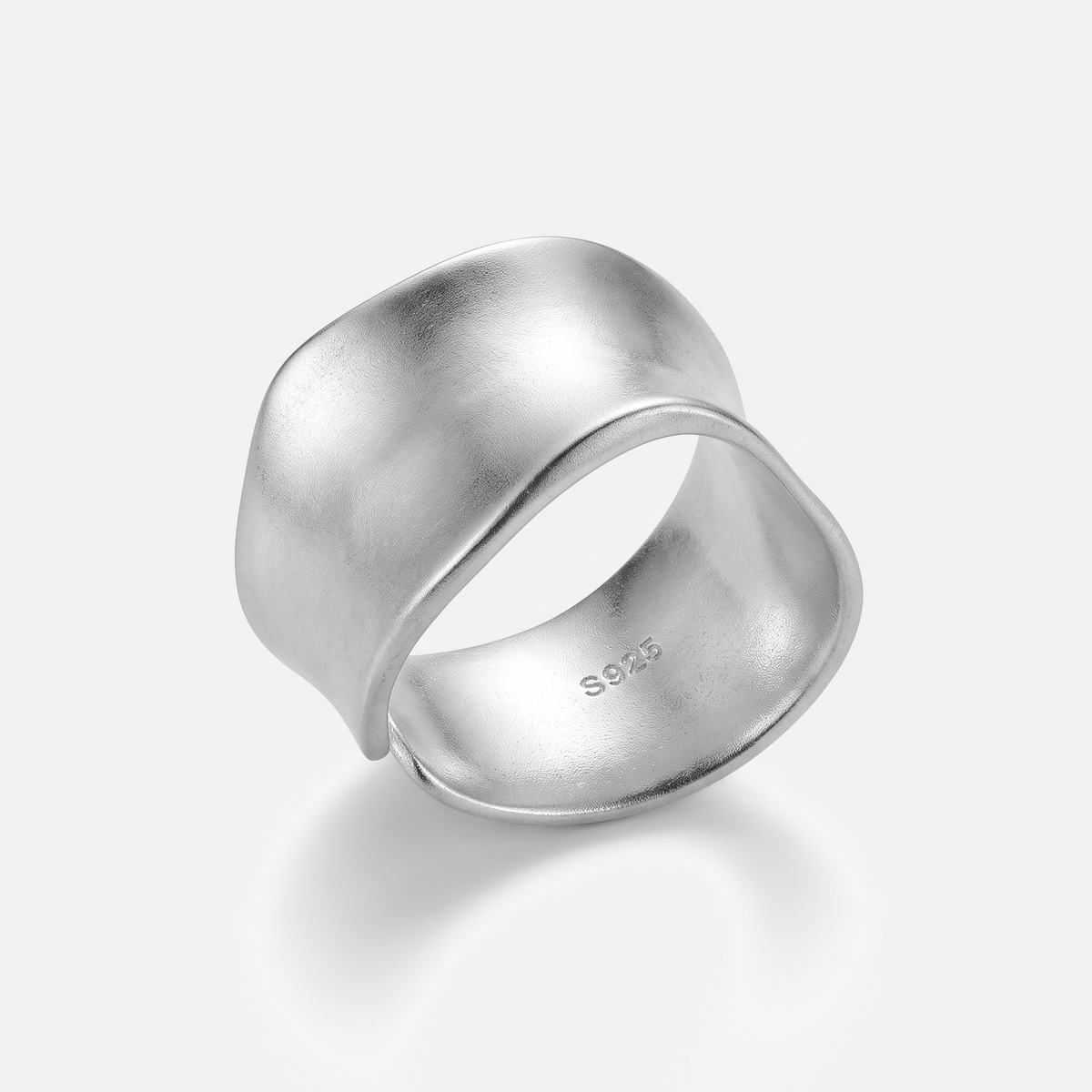 A wide, sculptural silver ring with a matte textured finish and a polished band, photographed on a clean light gray background. The inside of the ring is stamped with 'S925'.