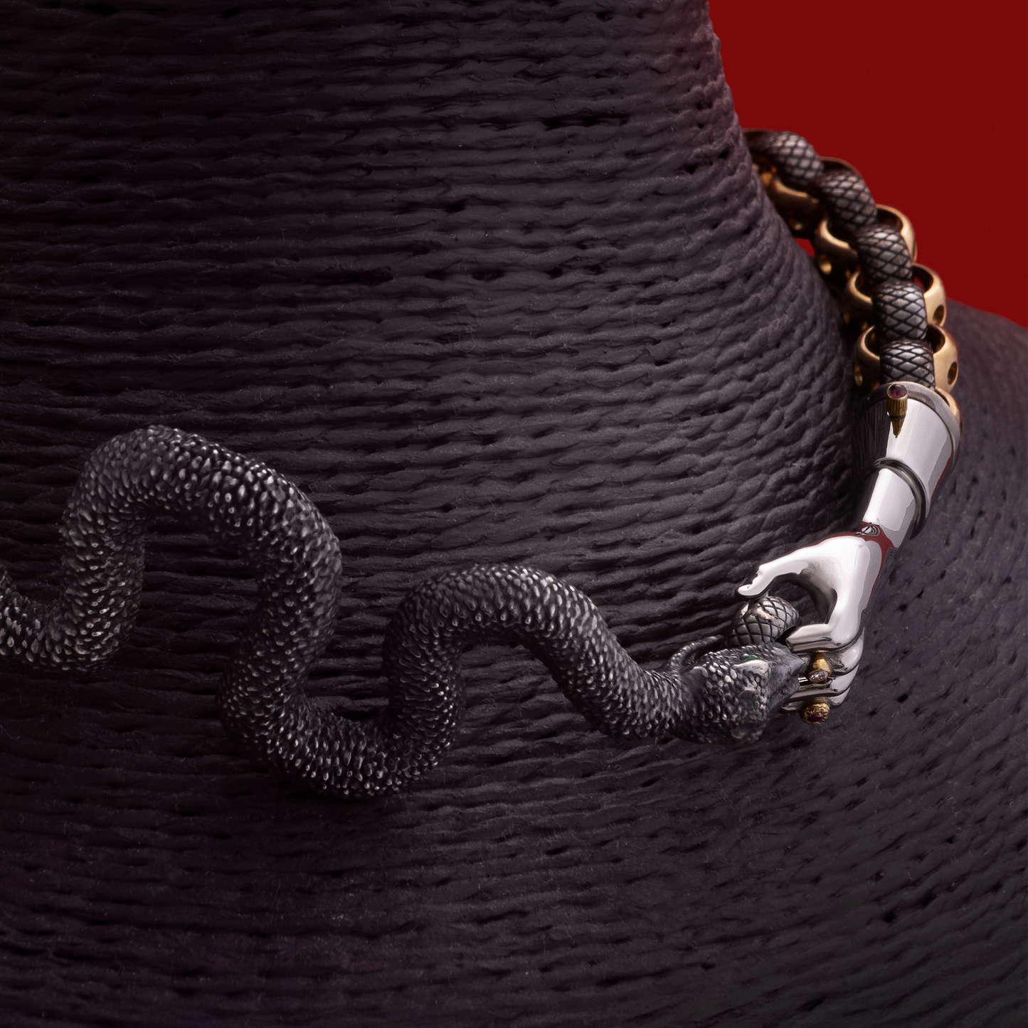 Close-up of snake jewellery clasp with hand detail in gold and black