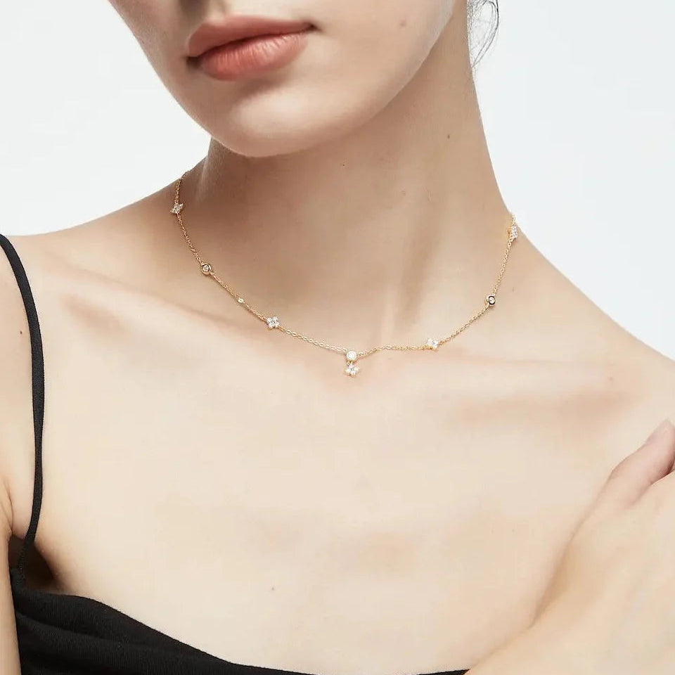 Gold necklace worn by a person against a neutral background
