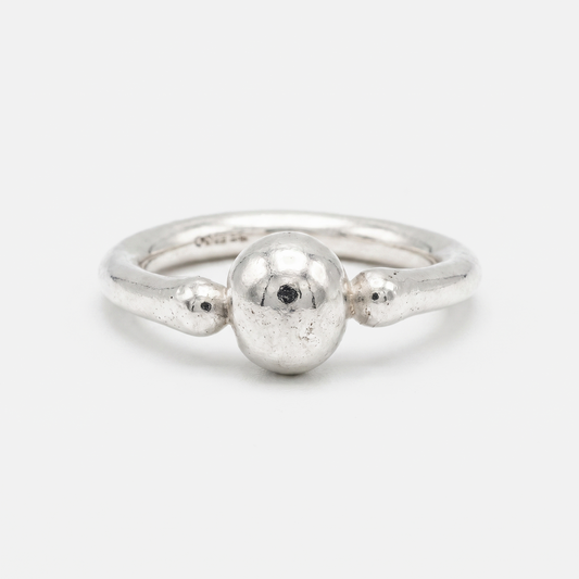 A sterling silver ring with a textured, organic-shaped band and a central polished oval bead, photographed on a clean white background.