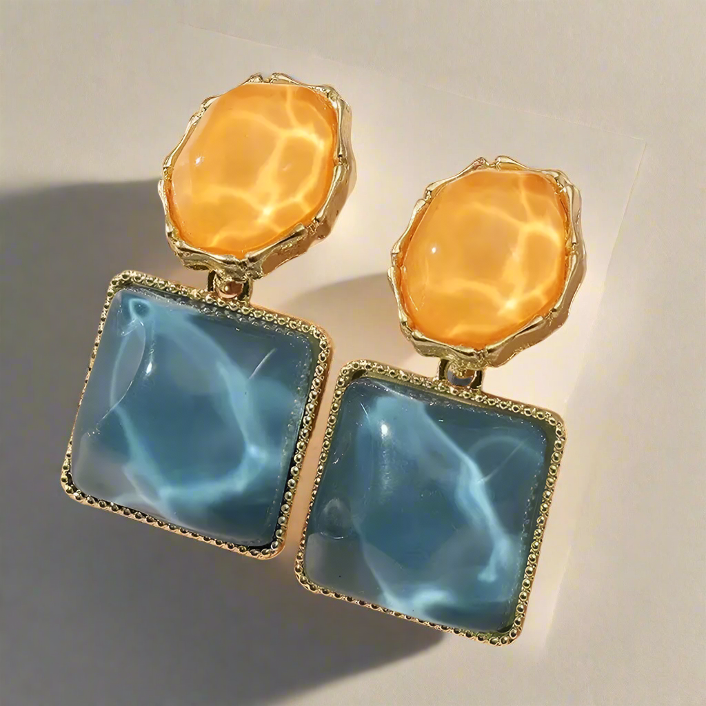 Pair of earrings featuring orange and blue stones on a light background