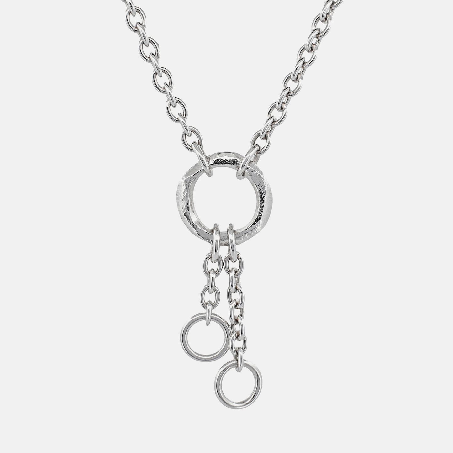A silver chain necklace featuring a textured circular ring pendant with two dangling chain loops at the bottom, shown against a light gray background.