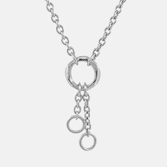 A silver chain necklace featuring a textured circular ring pendant with two dangling chain loops at the bottom, shown against a light gray background.