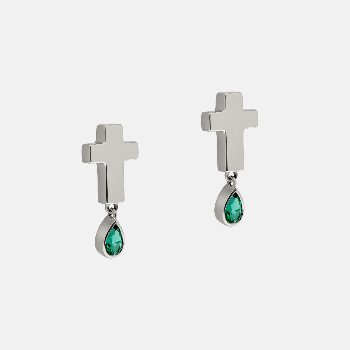 A pair of silver cross drop earrings with teardrop-shaped green gemstones, shown against a light gray background.