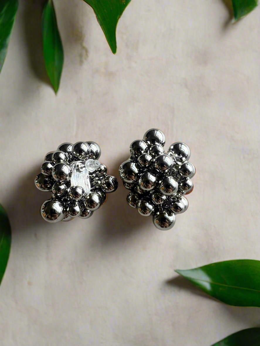 Silver bead earrings on a light background with green leaves