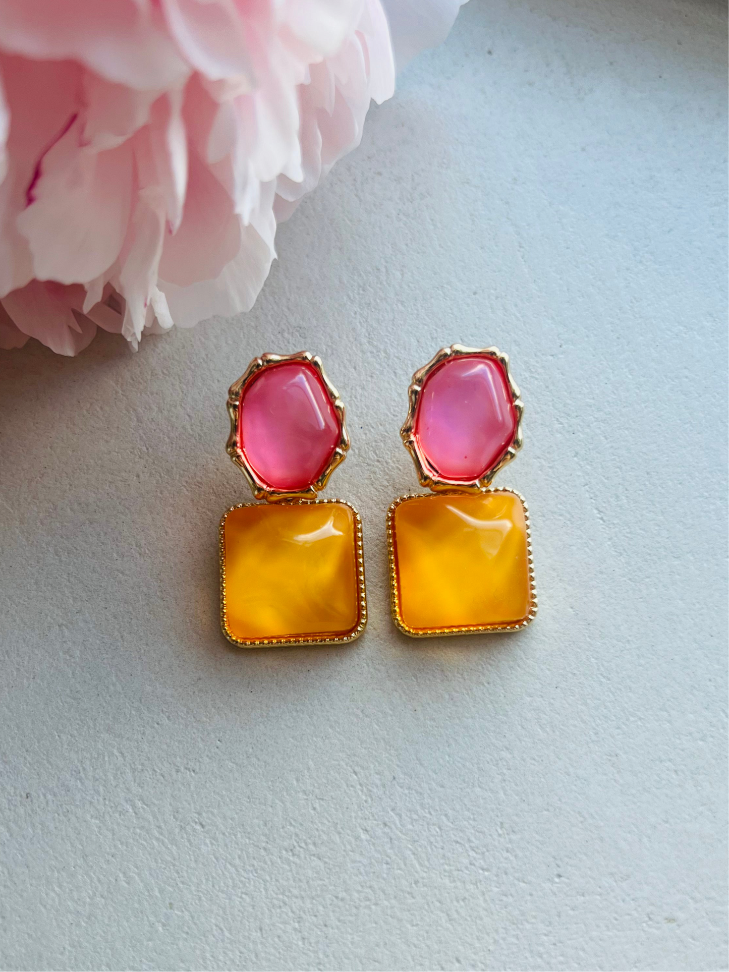 Pair of earrings with pink and orange stones on a light background
