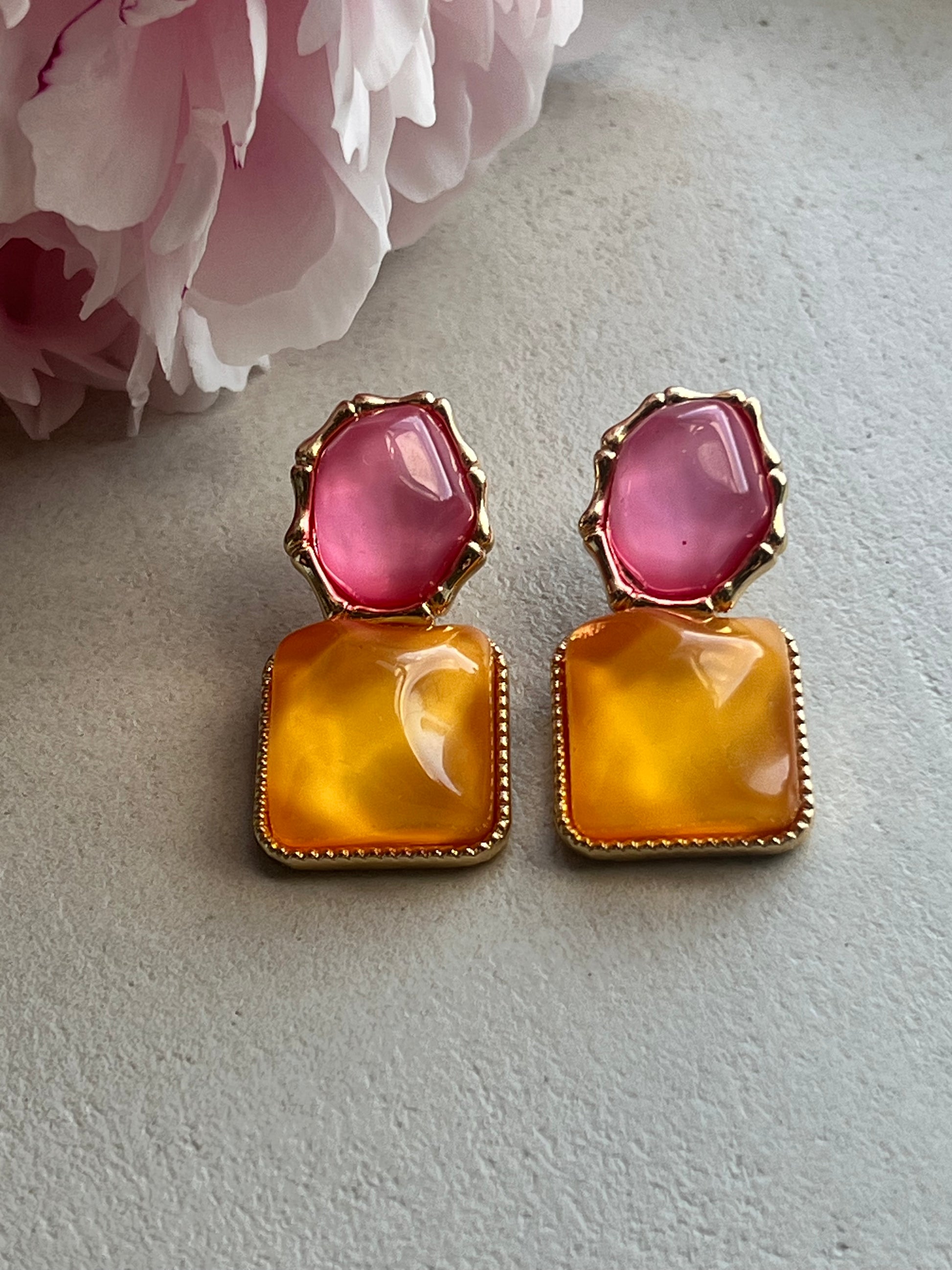 Pair of earrings with pink and orange stones on a light background