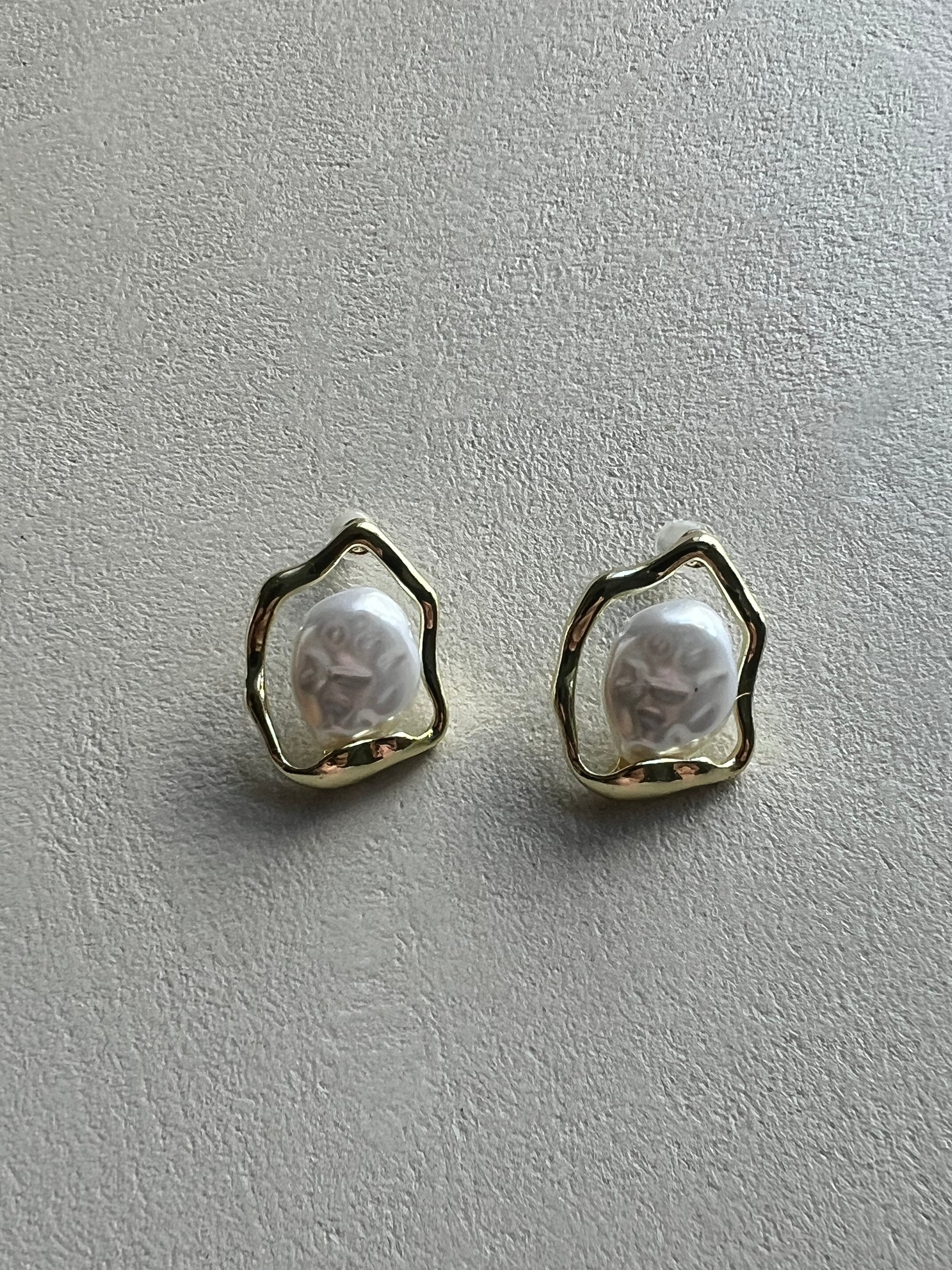 Pair of earrings with a textured design on a beige surface