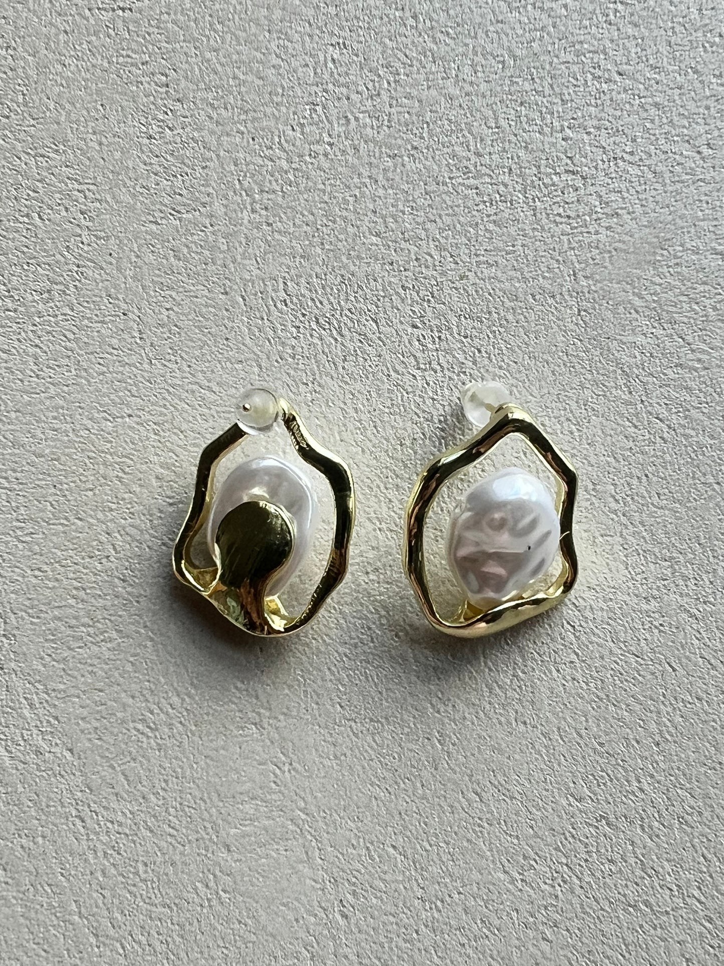 Pair of earrings with a textured design on a beige surface