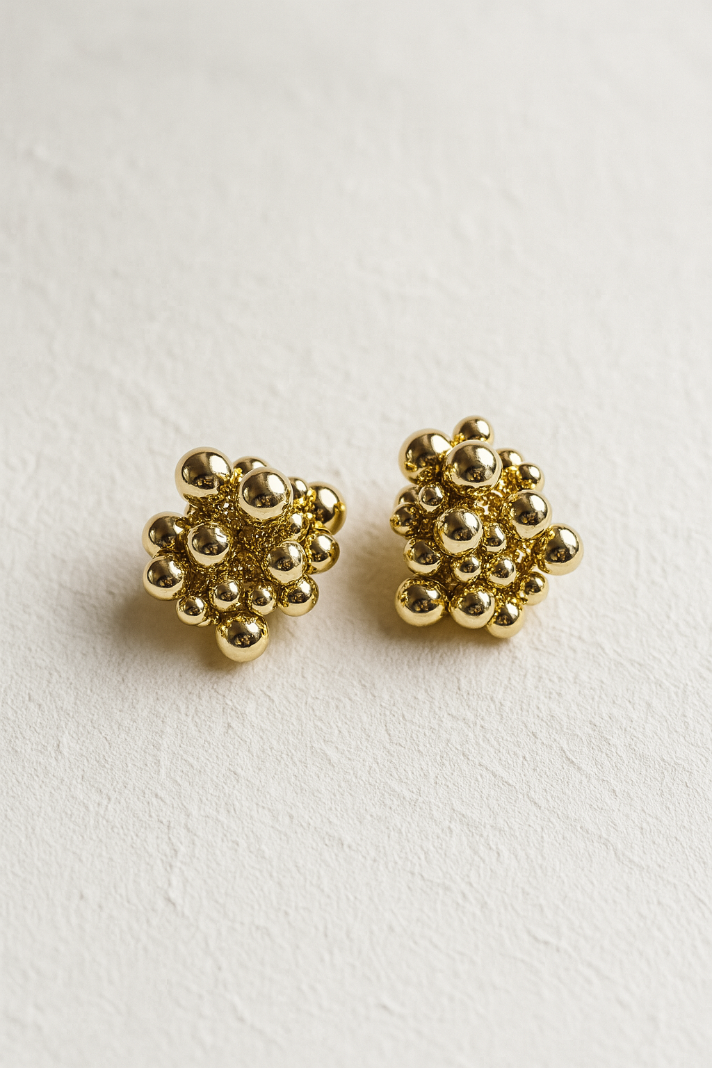 Pair of gold floral earrings on a light beige background