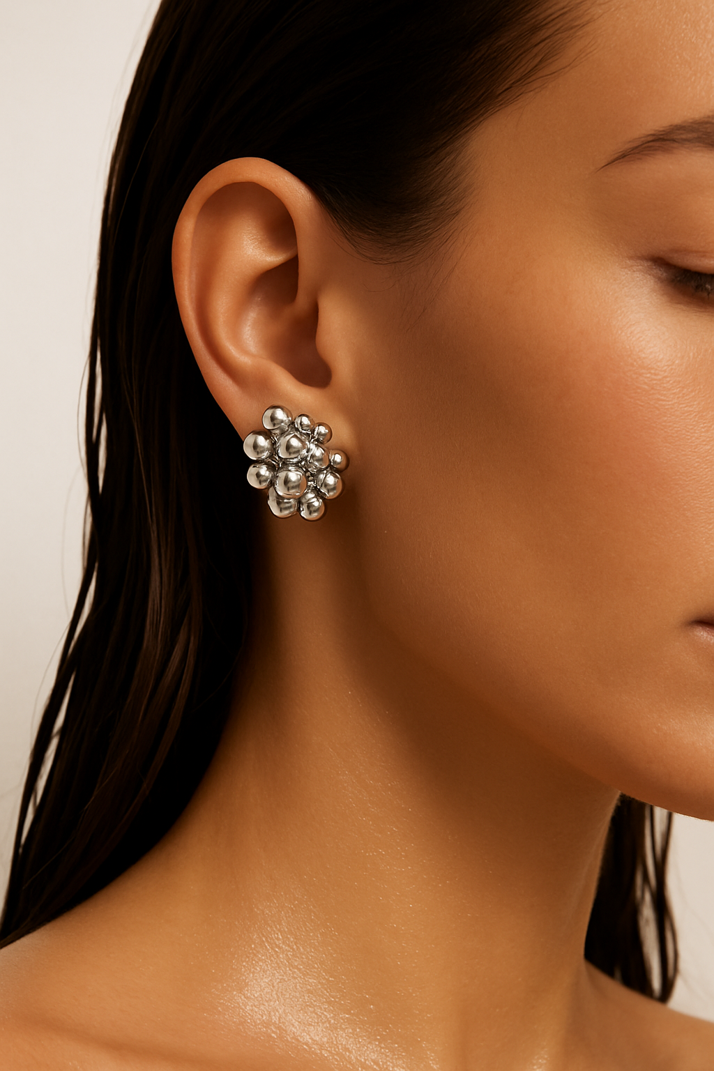 Close-up of a woman wearing silver floral earrings with a neutral background