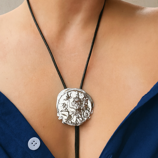 Silver medallion necklace on a person wearing a blue top