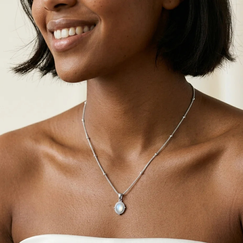 Woman wearing a silver necklace with a pendant on a neutral background