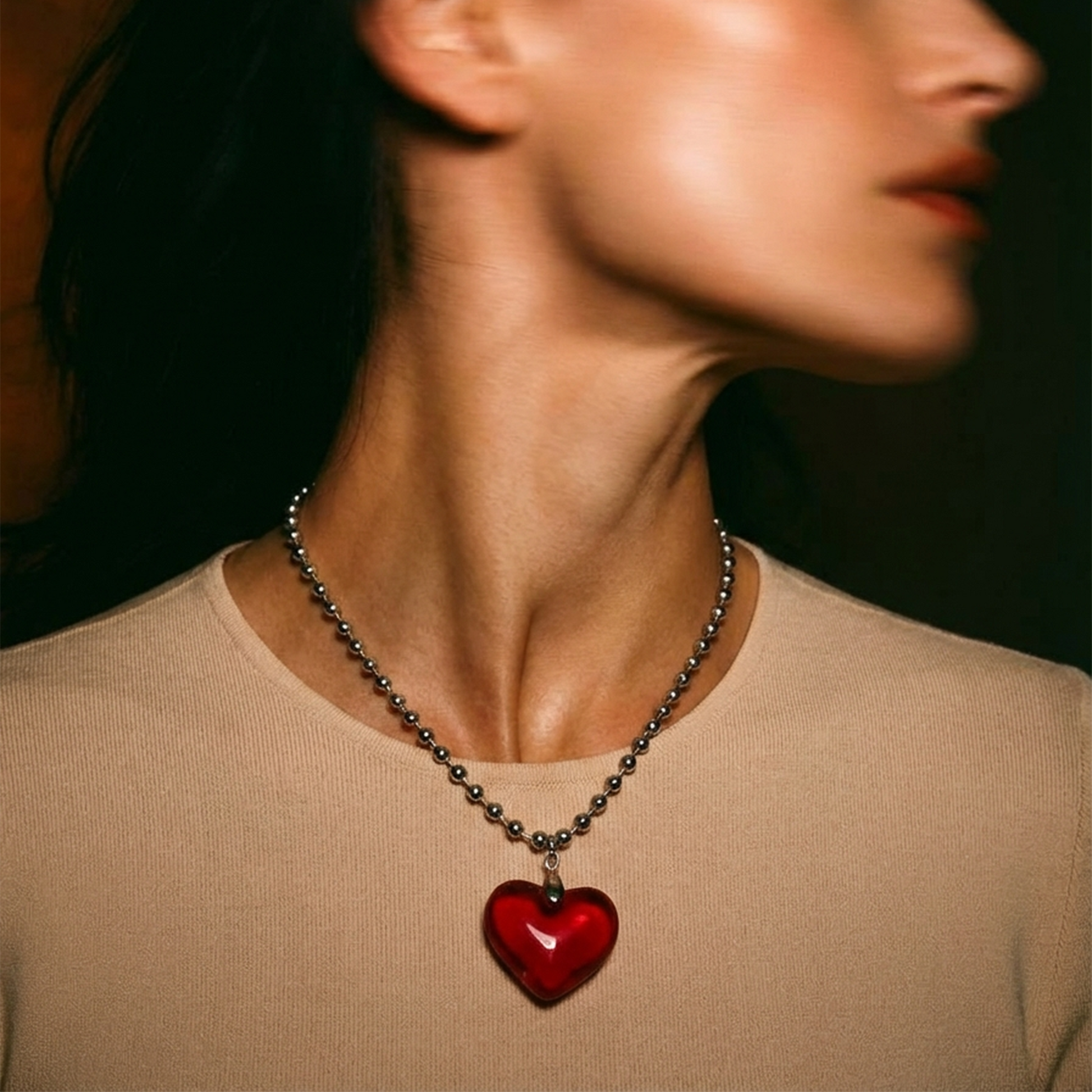 Person wearing a necklace with a red heart pendant