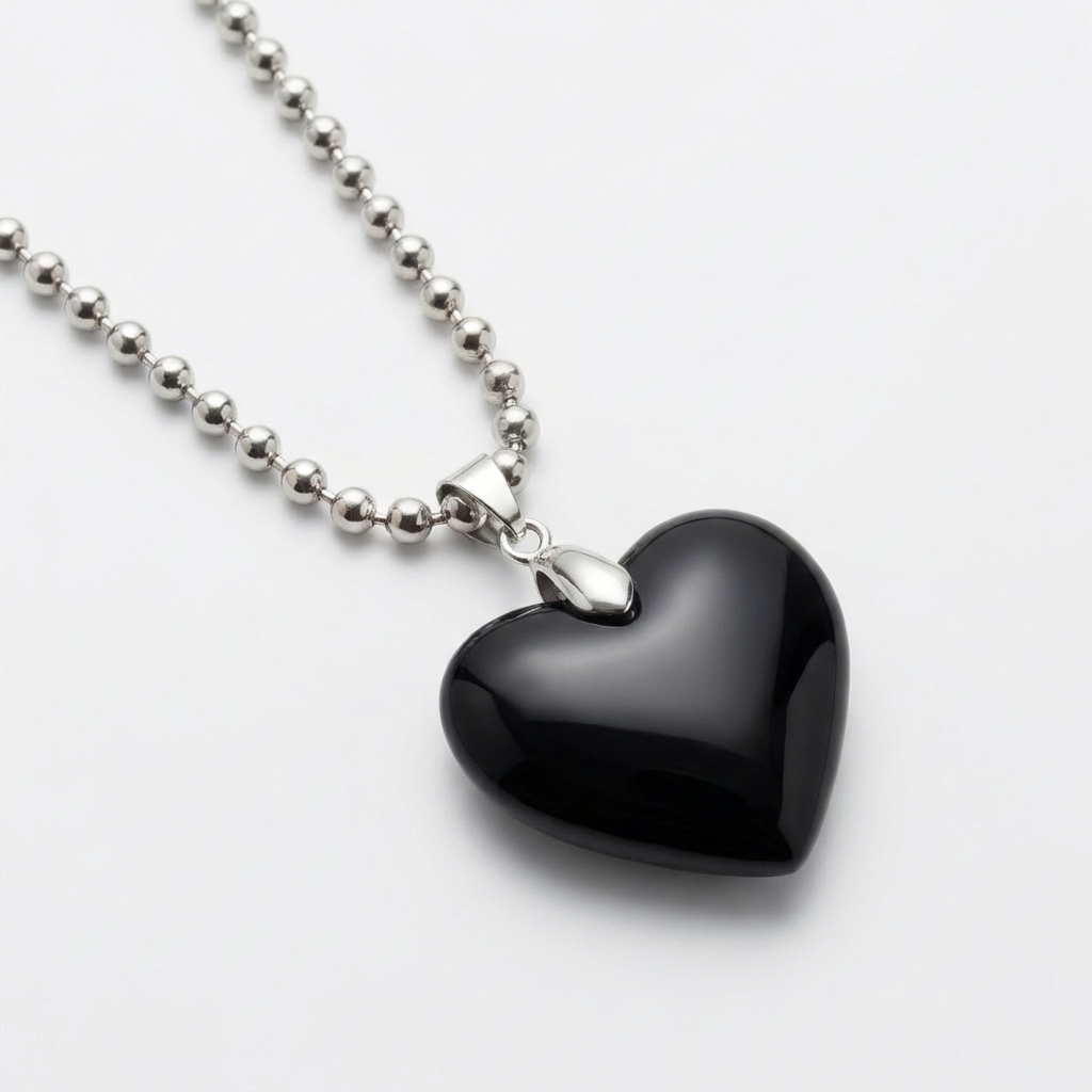 Black heart-shaped pendant on a silver chain against a white background