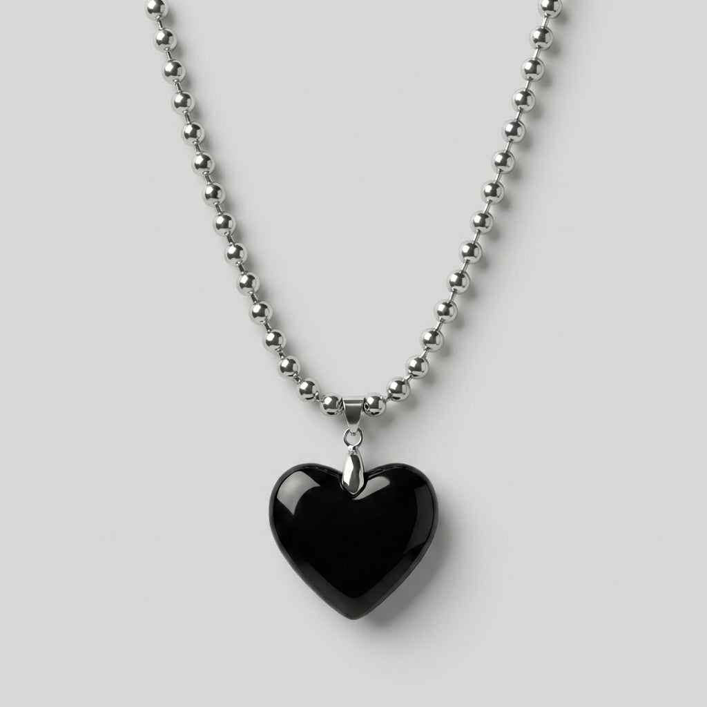 Black heart-shaped pendant on a silver chain against a white background