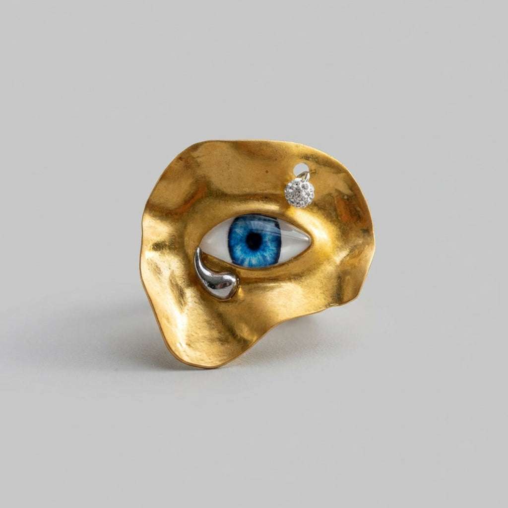 Gold ring with eye design on a gray background