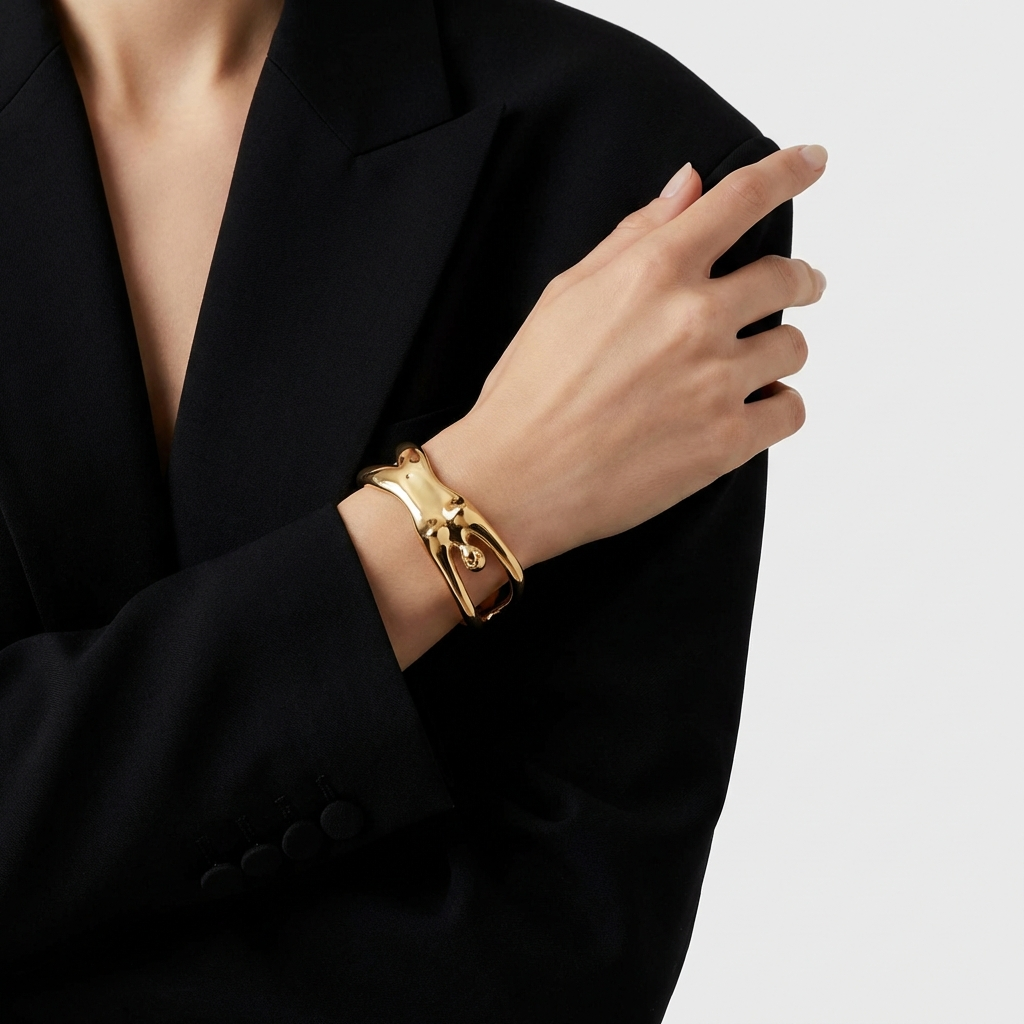 Gold bracelet on a person's wrist with a black blazer