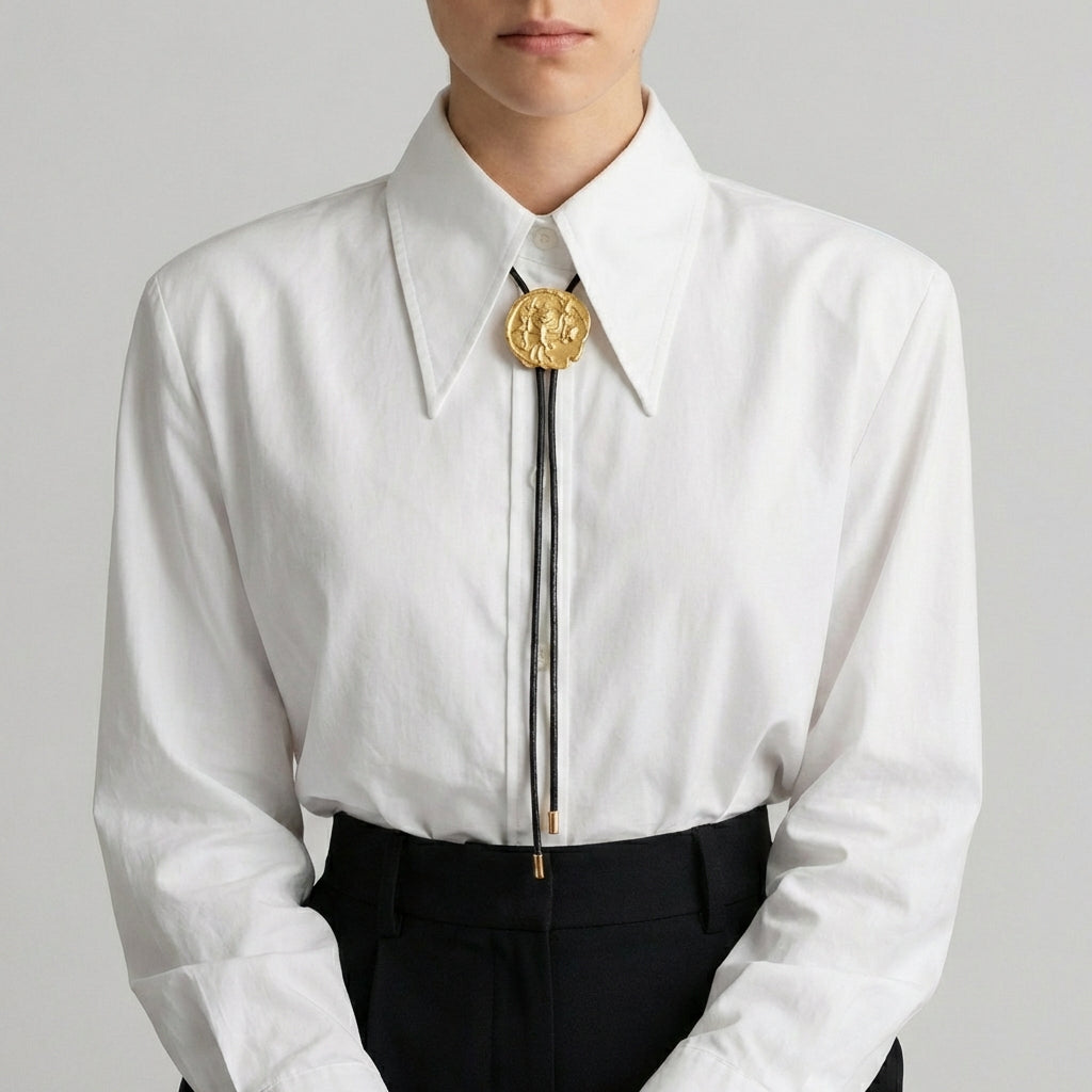 White shirt with a gold bolo tie on a plain background