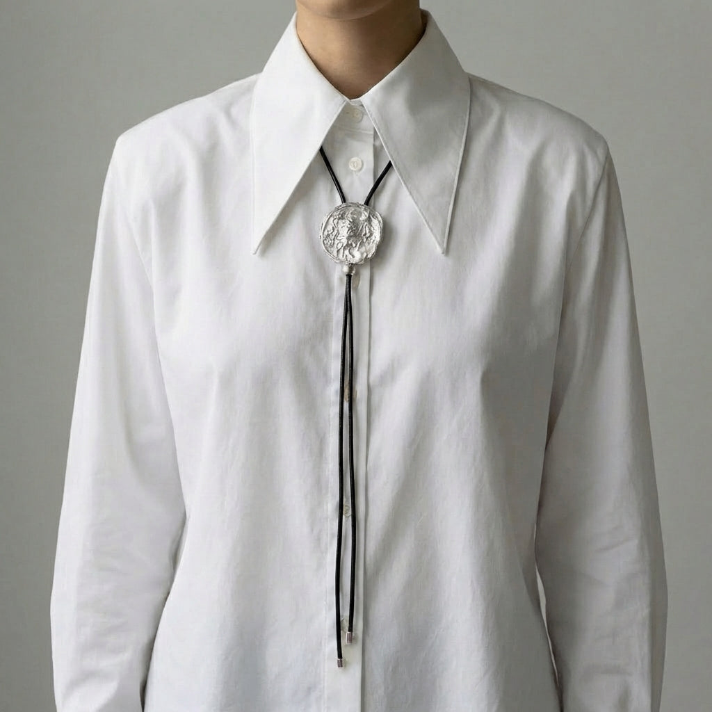White shirt with a silver bolo tie against a gray background