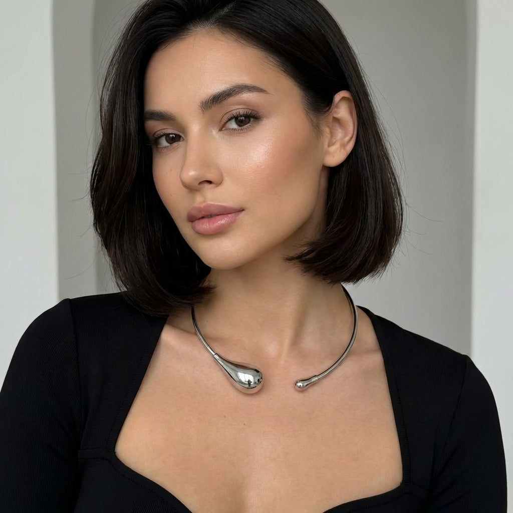Woman wearing a silver necklace against a neutral background