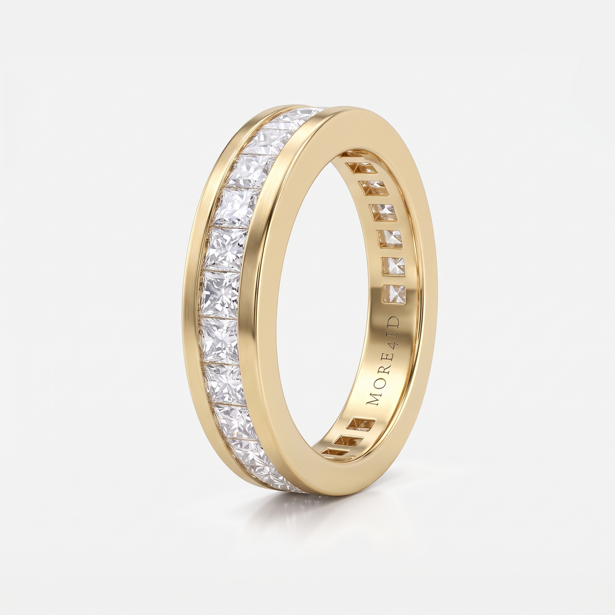 A yellow gold eternity ring featuring a channel-set row of clear rectangular diamonds on the front, shown on a clean white background. The brand name 'MOREA' is engraved inside the band.